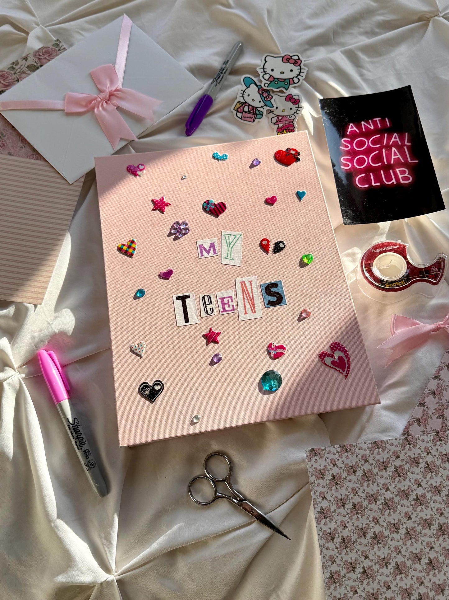 Light pink hardcover scrapbook with My Teens written in newspaper letters. Decorated with multicolored stickers and jewels.