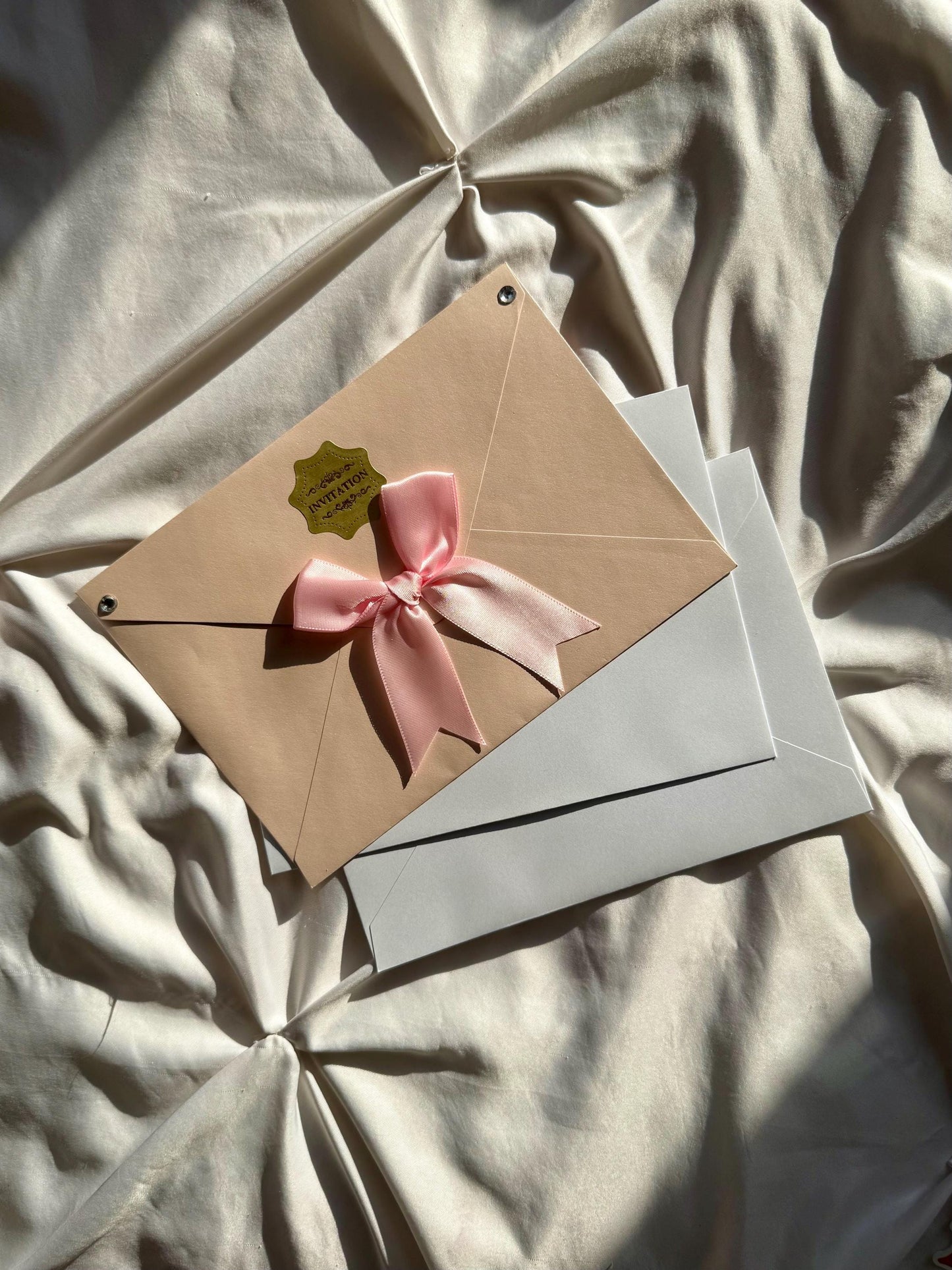 One pink wedding envelope with bow and two white envelopes.