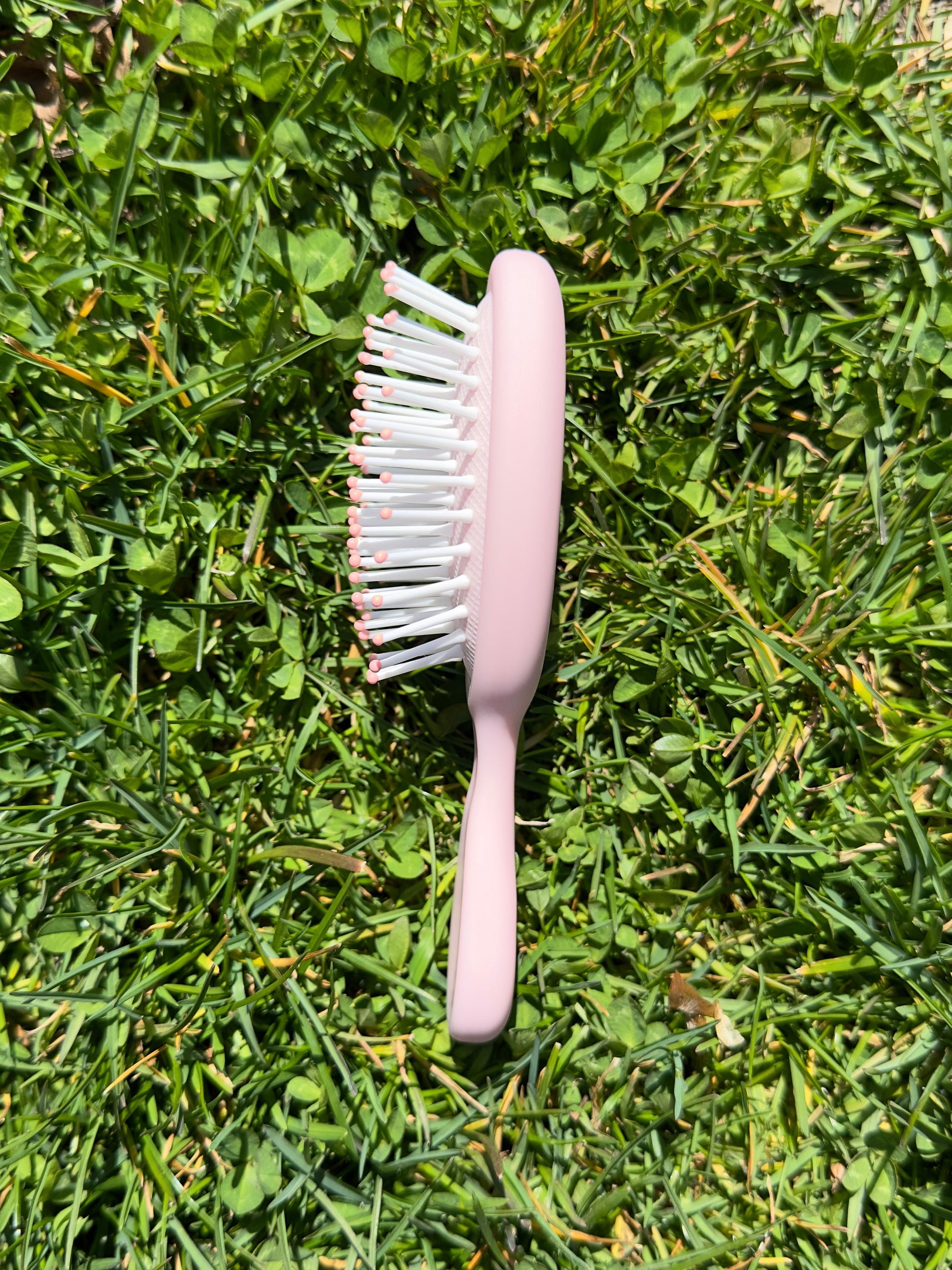 Side view of pink mini hairbrush