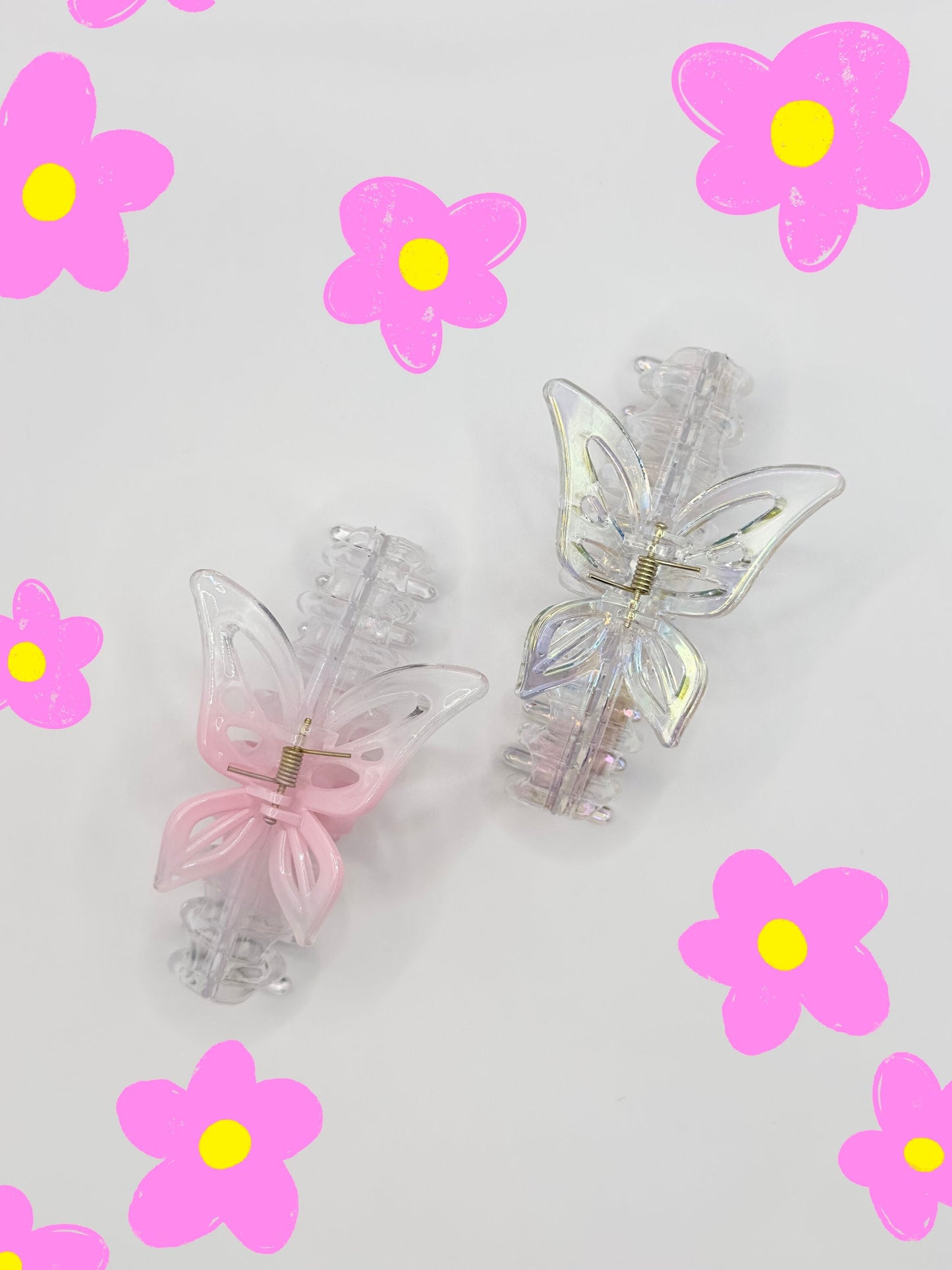 One ombre pink large butterfly hair clip and one translucent color with pink and yellow flowers drawn around them.