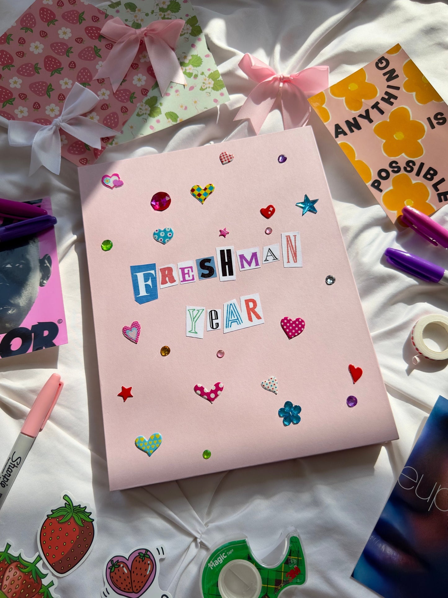 Light pink hardcover scrapbook with “Freshman Year” on cover written in newspaper lettering. Decorated with cute multicolored heart stickers and jewels.