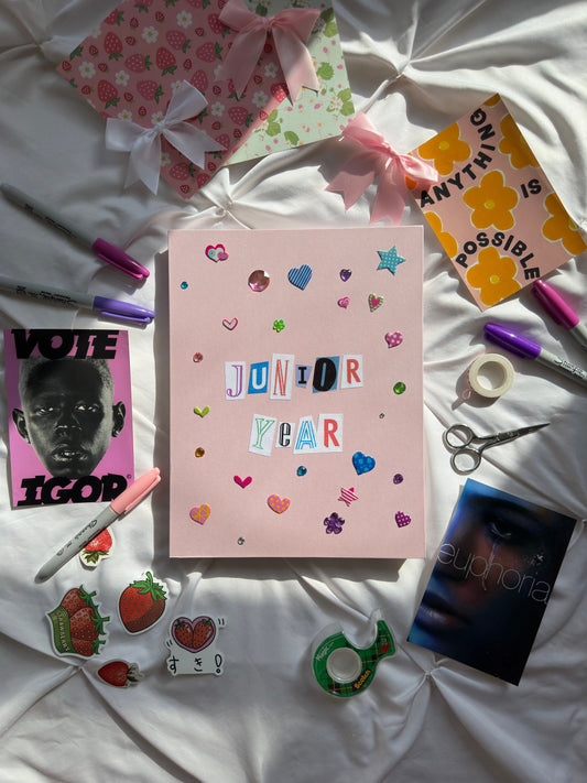 Light pink hardcover scrapbook with “Junior Year” newspaper letters on the cover. Decorated with heart and star stickers and jewels.